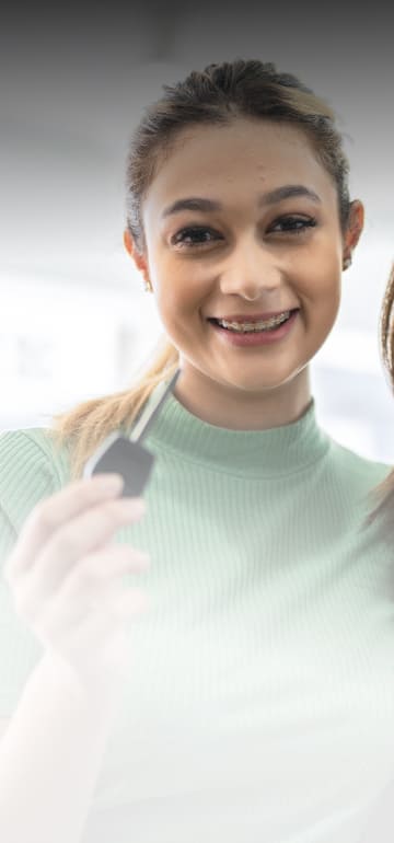 Consórcio Duas mulheres abraçadas sorrindo e uma com uma chave de carro na mão